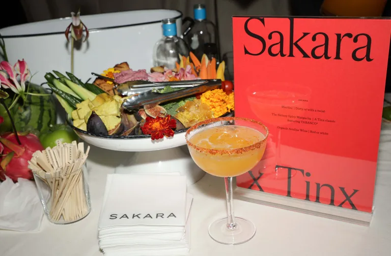 Shot of a table with fresh produce, a martini, and a red Sakara menu.