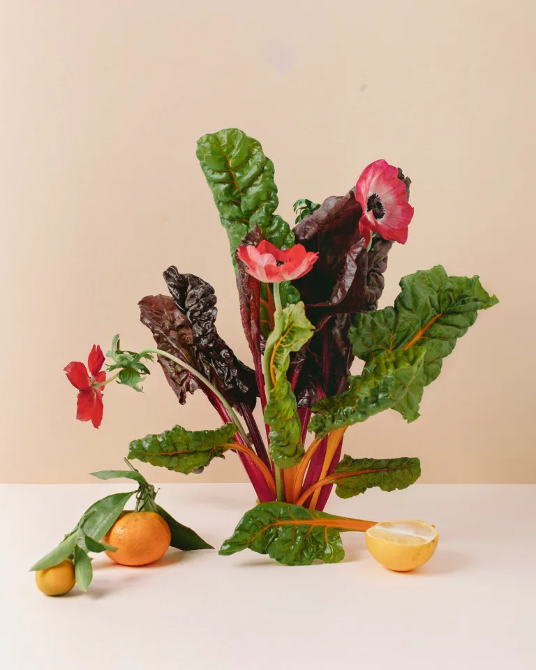 Image of a fresh produce bouquet, with kale leaves, pink flowers, and citrus.