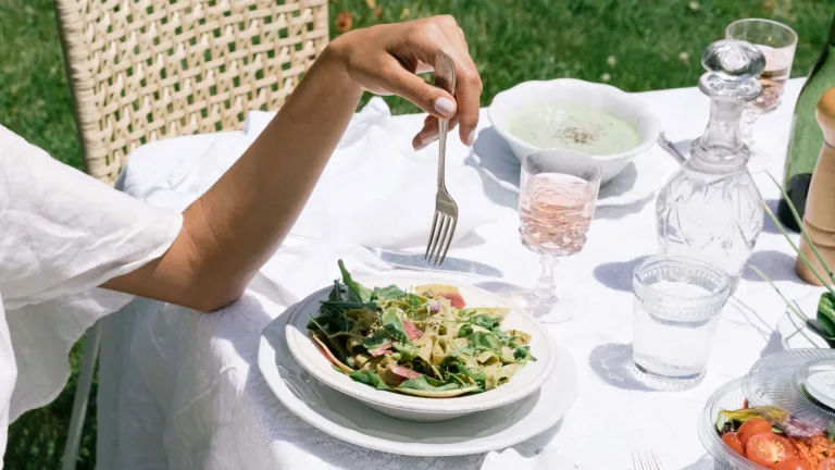 Outdoor table setting with a plate of salad and pink glassware.