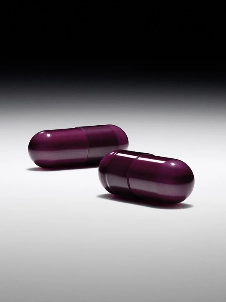 Two glossy purple capsules from Sakara Night Service sleep support supplement on gradient gray background