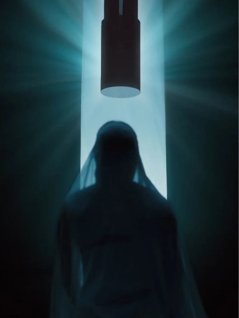 Silhouetted figure standing beneath dramatic overhead light with teal glow rays in dark studio setting