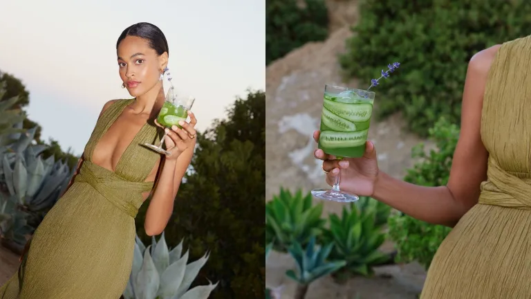 Woman outdoors in a green dress holding a green drink with cucumbers and a lavender stem.