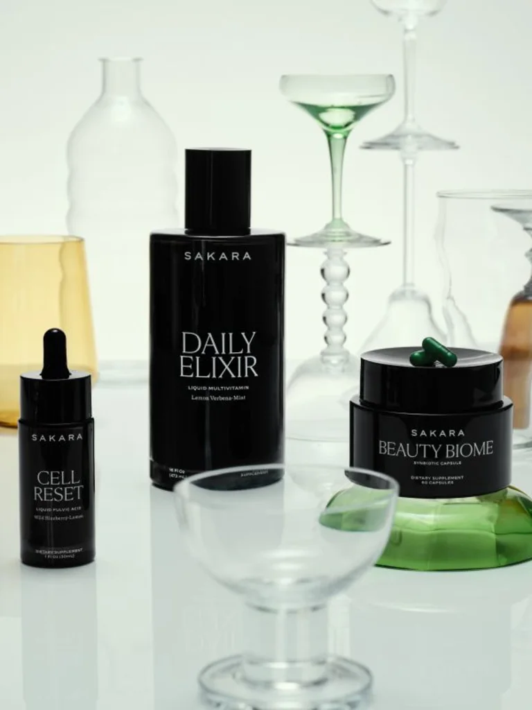 Sakara Skin Fundamentals Bundle with Daily Elixir, Cell Reset, and Beauty Biome supplements displayed with glassware and capsules.