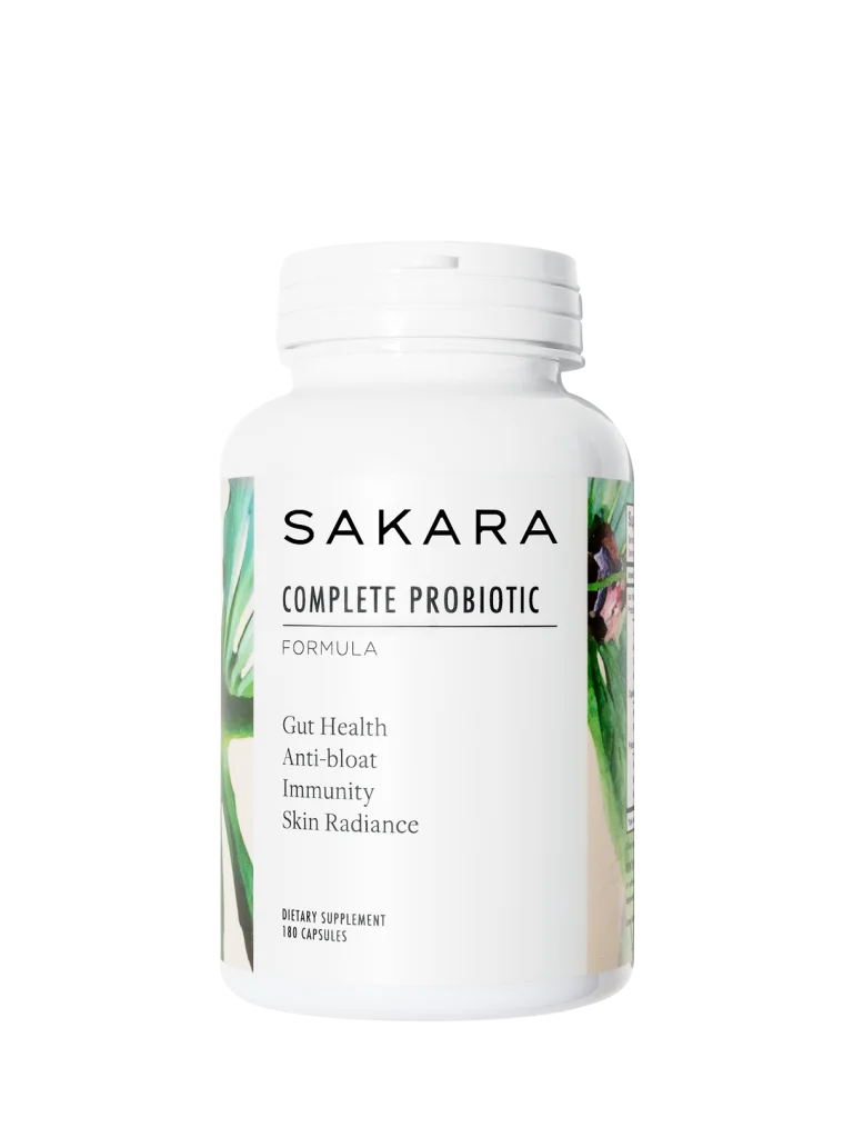sakara.momplete Probiotic Formula in white bottle with white cap, 90 capsules, labeled gut health, anti-bloat, immunity, and skin radiance, shown on grey background.